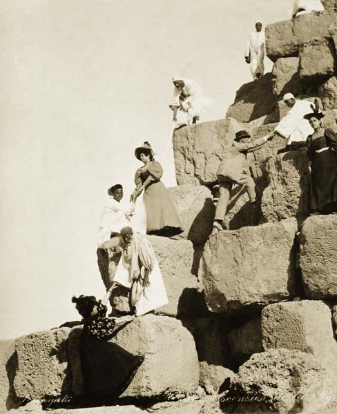 Tourists ascending the pyramids with native guides (b/w photo)  a English Photographer