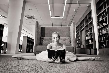 the Dreamer. ballerina on pointe shoes in the library reads a book holding it up