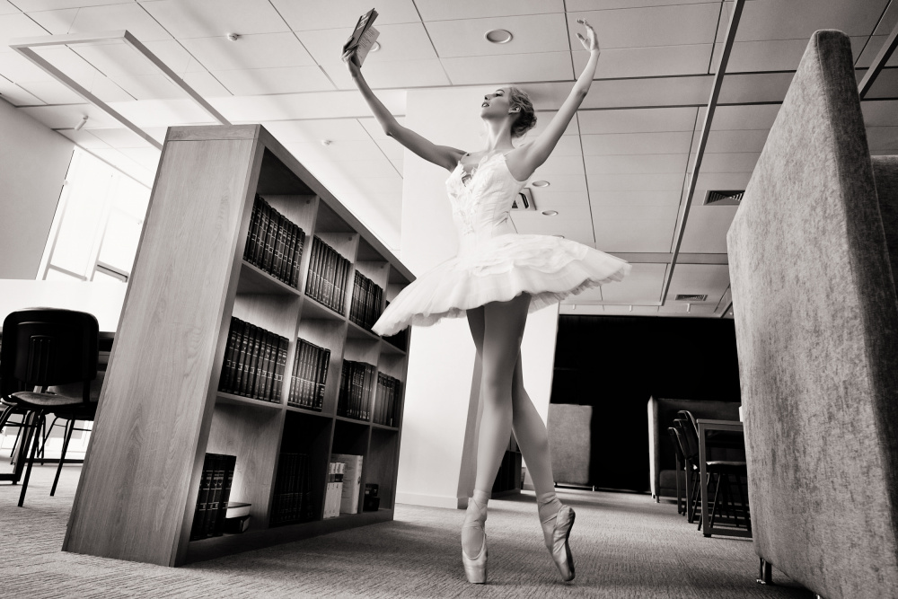 the Dreamer. ballerina on pointe shoes in the library reads a book holding it up a Alexandr