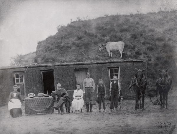 American pioneer family in front of their home (b/w photo)  a American Photographer