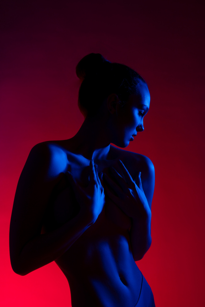 Young woman in casual clothes standing under neon light a Andrey Guryanov