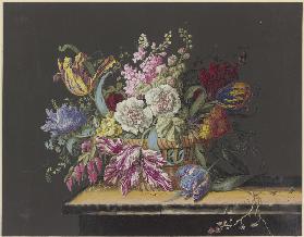 Blumenkorb mit Malven, Levkojen, Primeln, Tulpen und anderen Blumen auf einem Tisch