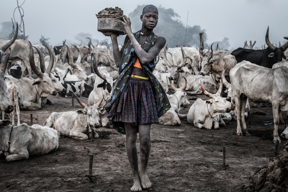 Woman carrying dung in a Mundari cattle camp - South Sudan a Joxe Inazio Kuesta Garmendia