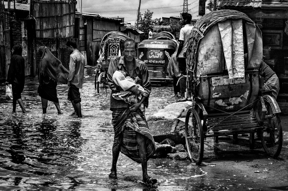 Man holding his child in the flooded streets of Bangladesh a Joxe Inazio Kuesta Garmendia