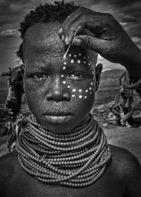 Painting the face of a karo tribe girl (Omo Valley-Ethiopia)
