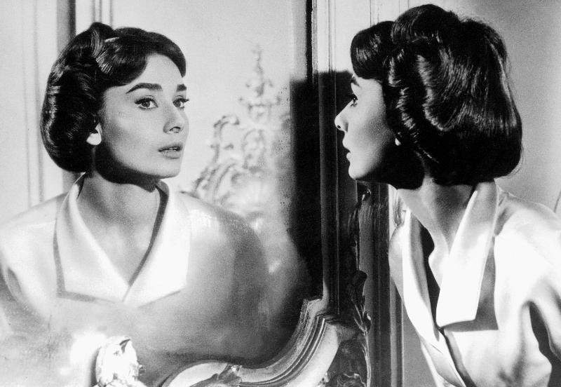 Actress Audrey Hepburn looking at her reflection in the mirror a 