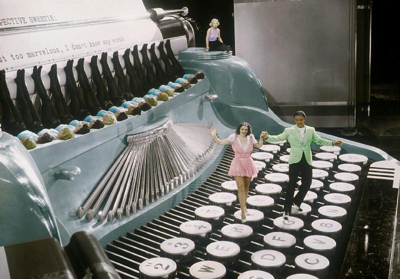 Couple dancing on the key of a giant typewriter, keys are leg of dancers, musical, 30's colourized d a 