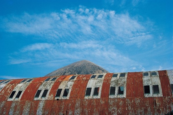 Rusted roof of a deserted warehouse with the breast of a mountain (photo)  a 