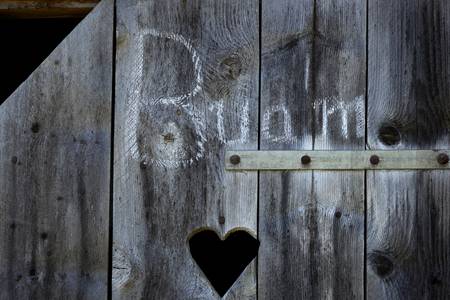 Plumsklo auf der Alm, mit einer Aufschrift Buam und einem Herz auf der Holztüre.